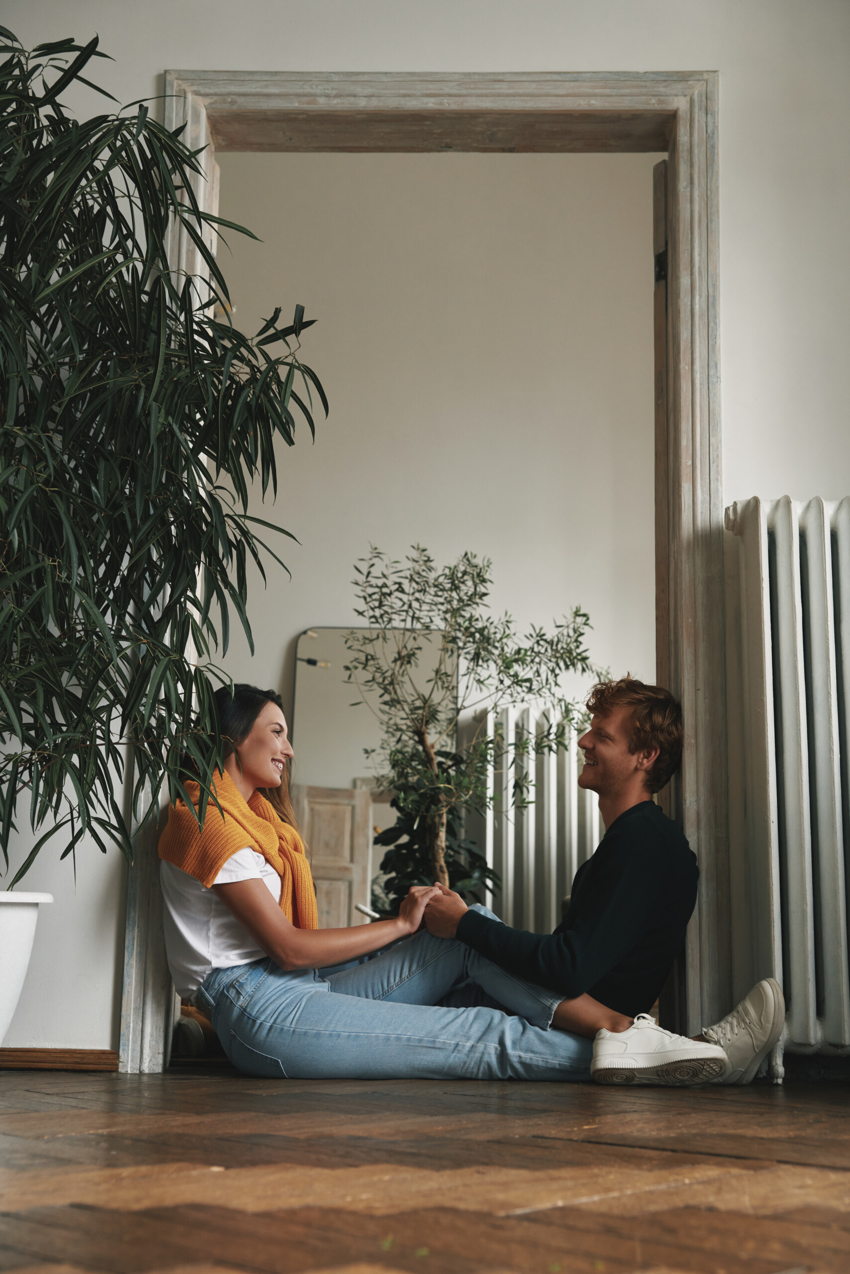 Happy young couple looking at each other while sitting on the floor at home